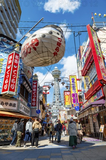 Lots of colorful signs in a pedestrian zone with shops and restaurants, behind Tsutenkaku Tower, Shinsekai, Osaka, Japan