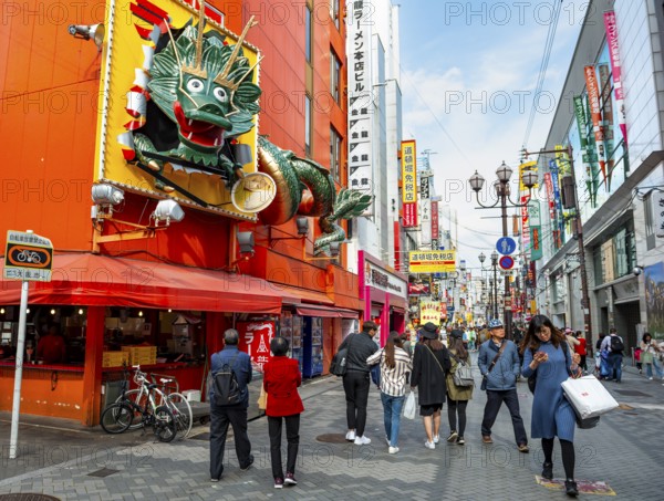 Dragon figure at a restaurant, lots of colorful signs in a pedestrian zone with shops and restaurants, Dotonbori, Osaka, Japan