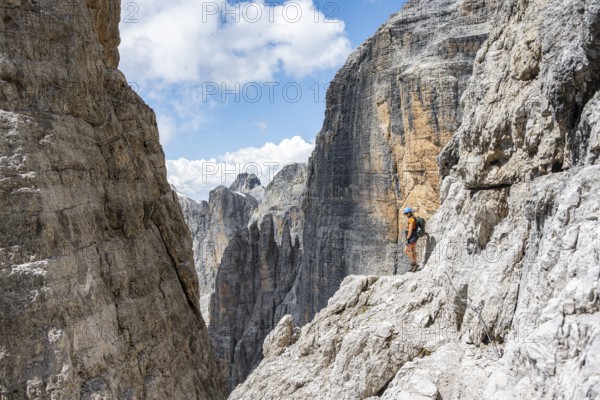 Hikers on the Sentiero Brentari via ferrata in front of cliffs, Brenta Mountains, Brenta-Adamello Natural Park, Trentino, Italy