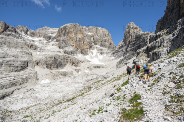 Hikers on hiking trail, behind Cima Margherita and Cima Tosa, Brenta Mountains, Brenta-Adamello Natural Park, Trentino, Italy