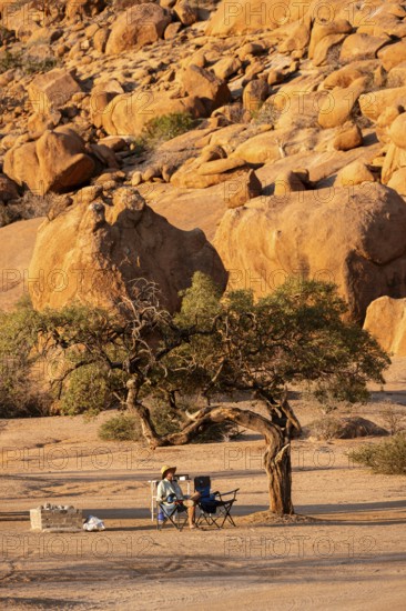 Secluded campground with a tree in the desert of Spitzkoppe, surrounded by large rock formations, Spitzkoppe, Namibia
