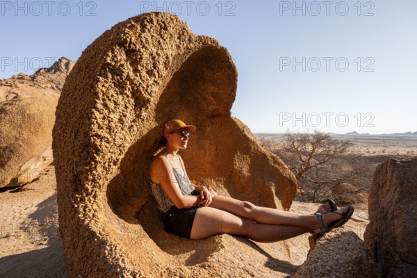 Woman relaxing in a naturally shaped rock in the desert, Spitzkoppe, Namibia