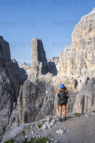 Female hiker in front of Campanile Alto and Cima Brenta Alta, Bocchette Centrale band trail, via ferrata in the Brenta Mountains, Parco Naturale Brenta-Adamello, Trentino, Italy