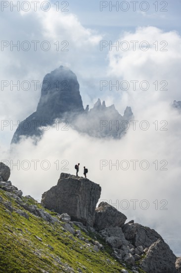 Alpine panorama, mountaineers on a large rock, fog and Torre Di Brentai and Cima Tosa, rocky mountain peaks and mountain landscape, Brenta Mountains, Parco Naturale Brenta-Adamello, Trentino, Italy
