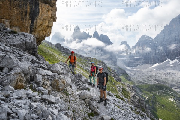 Climbers on a hiking trail, rocky mountain landscape with fog, Via Ferrata SOSAT via ferrata, Brenta Mountains, Trentino, Italy
