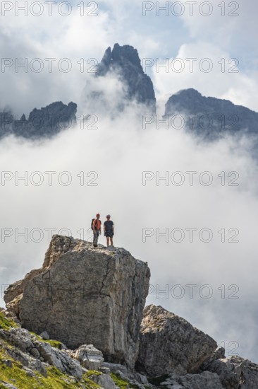 Mountaineers on a large rock, fog and Torre Di Brentai, rocky mountain peaks and mountain landscape, Brenta Mountains, Brenta-Adamello Natural Park, Trentino, Italy