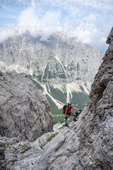 Female mountaineer on rock face, rocky mountain landscape, Via Ferrata SOSAT via ferrata, Brenta Mountains, Trentino, Italy