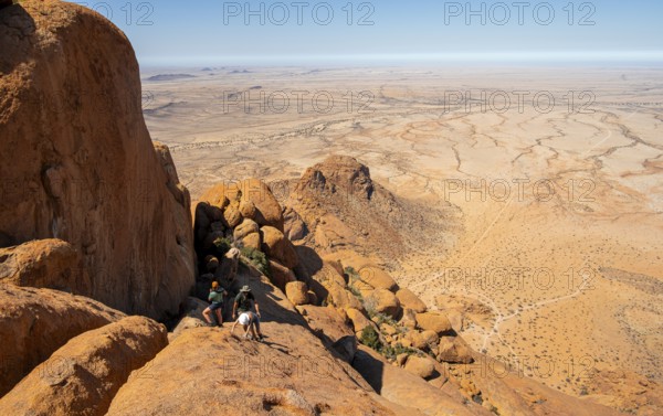 View from a rock of vast, dry desert landscape under clear sky, Spitzkoppe, Namibia