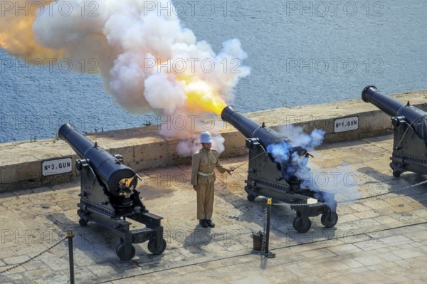 Soldier firing cannon salute with SBBL 32-pounder gun at 16th century Saluting Battery at Grand Harbour in capital city Valletta on the island Malta
