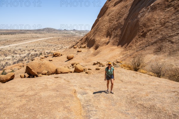 Female hiker explores an impressive rocky landscape in the Namibian desert, Spitzkoppe, Namibia