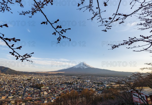 View of Mount Fuji volcano over Fujiyoshida City in evening light, at sunset, Arakurayama Sengen Park, Yamanashi Prefecture, Japan