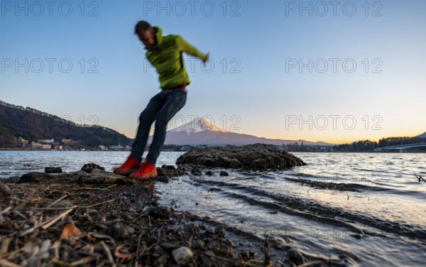 Young man jumping, Lake Kawaguchi, view of Mount Fuji volcano at sunset, Yamanashi Prefecture, Japan