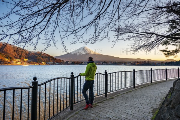 Tourist on Kawaguchi Lake waterfront, view of Mount Fuji volcano at sunset, Yamanashi Prefecture, Japan