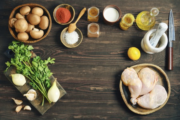 Top view of food ingredients for cooking including chicken meat, vegetables, spices and herbs arranged as frame on dark rustic wooden background with copy space