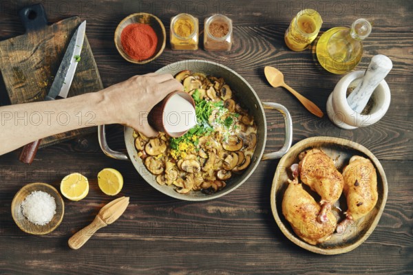 Pouring heavy cream to a pot filled with fried onion and mushrooms. Process of preparing creamy mustard sauce for roasting chicken legs