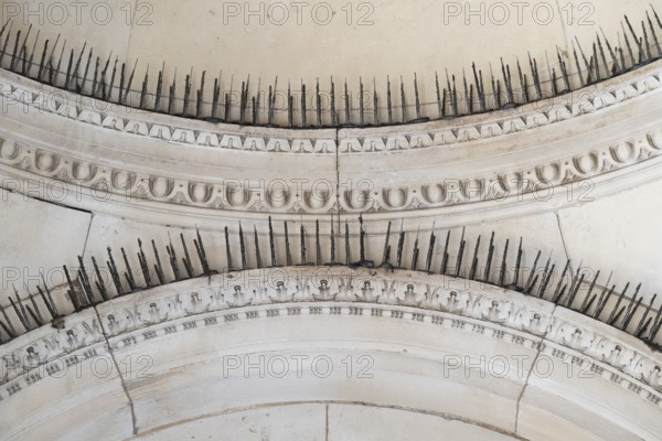 Stone arches with decorative ornaments and long metal spikes to repel pigeons, Royal Academy of Arts, Art Gallery and College of Arts, Burlington House, Piccadilly, London, England, Great Britain