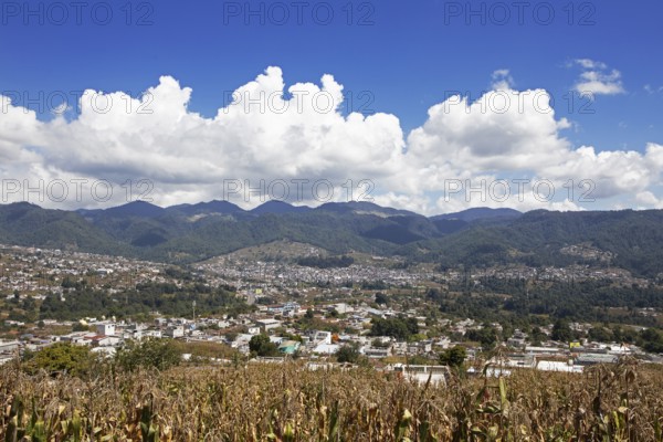 City view of Nahualá between green mountains, in front of a corn field, highlands, Sololá Department, Guatemala