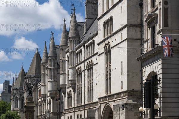 Royal Courts of Justice, neo-Gothic architecture with towers and British flag under blue sky, London, England, Great Britain