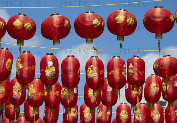 Red Chinese lanterns hanging on yellow lines against a blue sky, London, England, Great Britain
