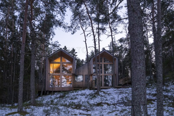 Internally illuminated modern wooden house in a wintery forest, cozy atmosphere, Korpoström, Korpo or Korppo, southwestern archipelago, Finland