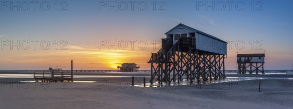 Stilt houses at low tide on the beach at sunset, St. Peter-Ording, Schleswig-Holstein Wadden Sea National Park, Schleswig-Holstein, Germany