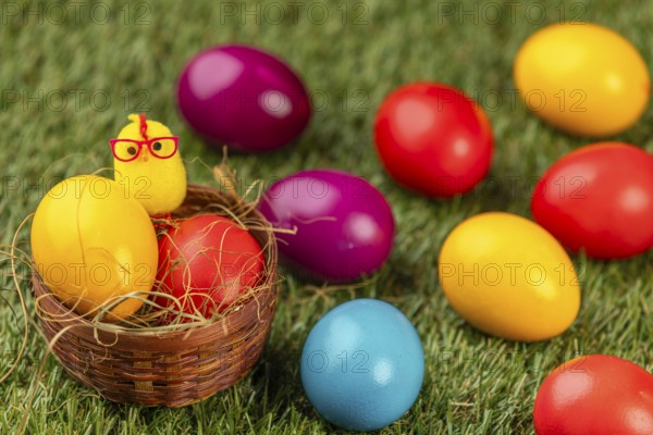 Colourful easter eggs and a chick figure on green grass