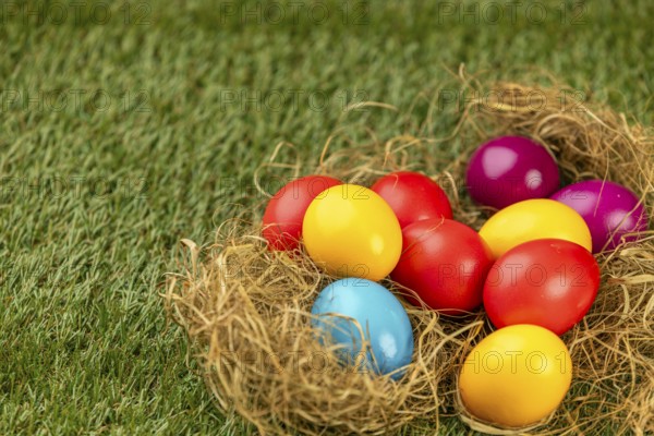 Colorful Easter eggs in a straw nest on green grass