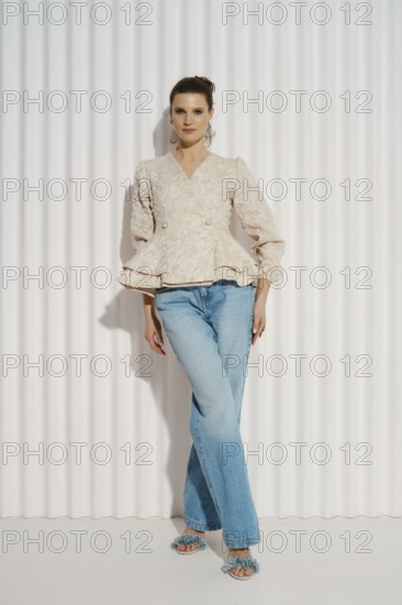 A model stands confidently in a well-fitted top and jeans. She has her left hand on her hip and her right hand resting by her side