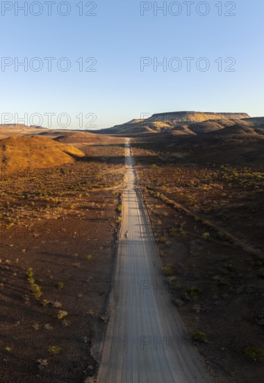 Aerial view, infinite space, straight road leads through dry desert landscape, hills in Damaraland, Namibia
