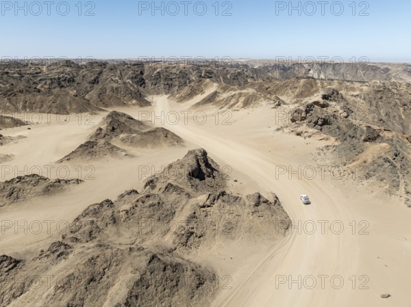 Aerial view, dry barren mountains in Moon Valley, road with car, rocky landscape ridged by erosion, Namib-Naukluft Park, Namib Desert, Namibia
