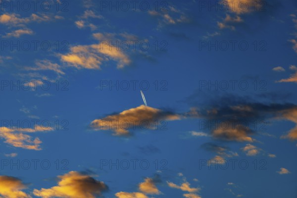 Aircraft contrails with red clouds, sunrise, Upper Austria