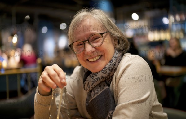 Elderly woman, portrait, glasses, gray hair, scarf, drink, straw, sitting in a bar, restaurant, laughing heartily, Stuttgart, Baden-Württemberg, Germany