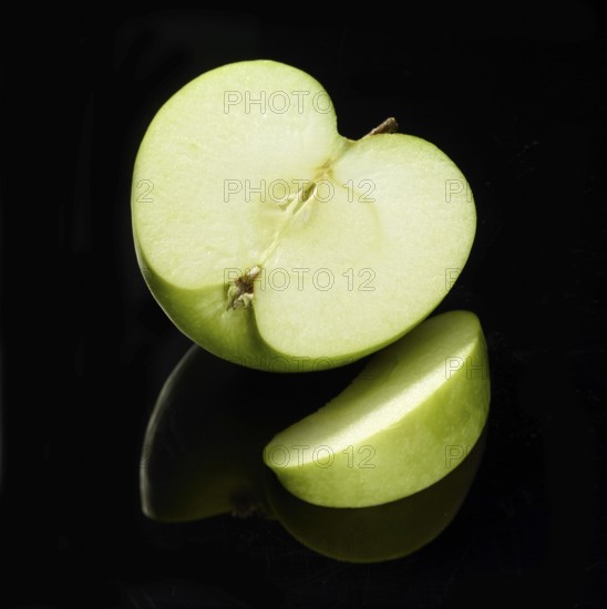 Apple, apple half and apple cleft (Malus domestica) in front of a black background, studio shot