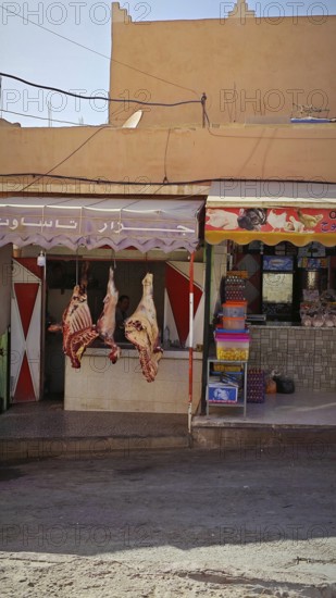 Local butcher shop with hung meat in front of a traditional house in a market, southern Morocco