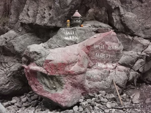 A rock with red and white inscriptions and small decorative objects, welcome, Atlas, Imlil, Morocco
