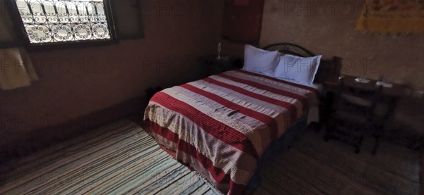 Cozy bedroom with a striped duvet cover and traditional wood decor, Morocco