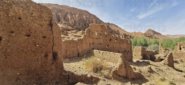 Ancient sandstone ruins in a dry, rocky landscape with sparse vegetation, Morocco