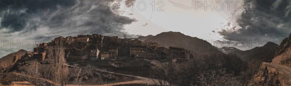 A dramatic panorama of a mountain village with dark clouds in the sky, Atlas Mountains, Morocco