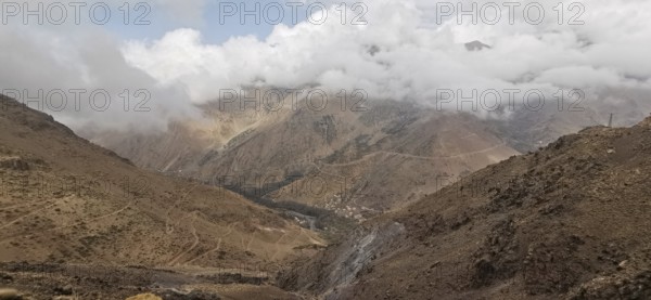 A barren mountain landscape under a cloudy sky with visible trails, Atlas Mountains, Morocco