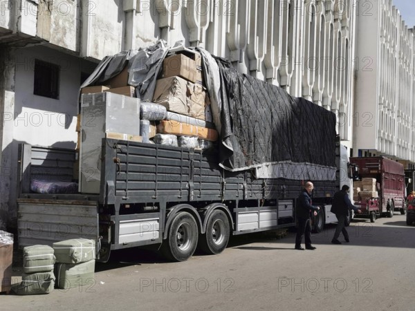 Large truck on the road, heavily loaded with boxes and covers, next to building, load securing, Casablanca, Morocco