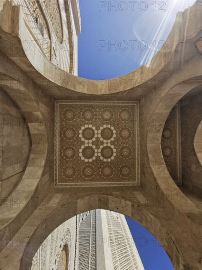 View from below of an ornate stone dome with geometric patterns and blue sky in the background