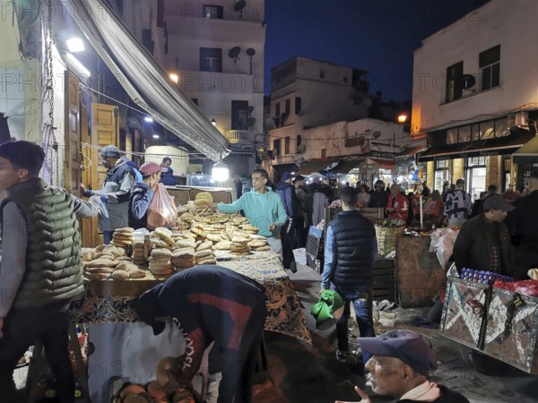 Bustling night market with bread stalls, people moving in a confined space in the Medina of Casablanca, Morocco