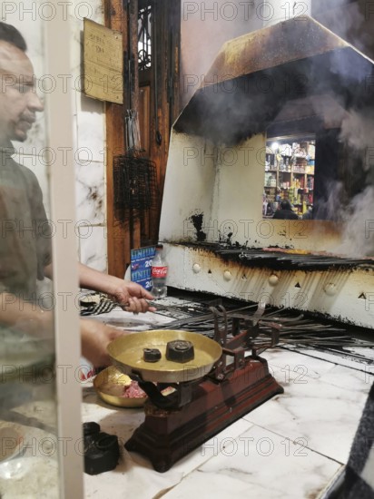 Man preparing food at a smoky oven in the Medina of Marrakech, Morocco