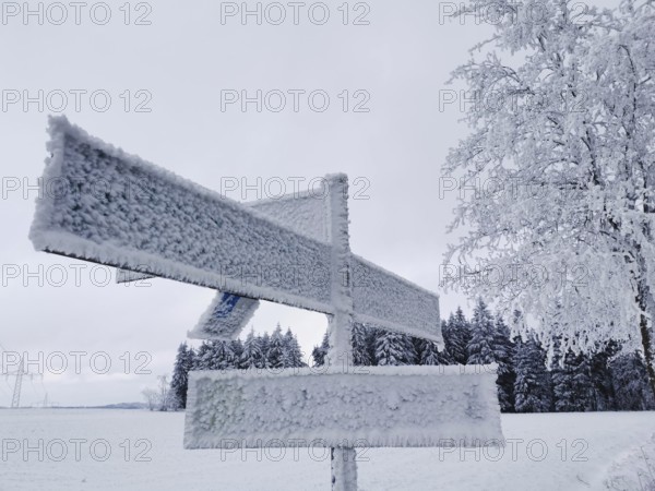 Icy trail sign covered with snow in a snowy winter landscape, Rennsteig, Frankenwald nature park Park