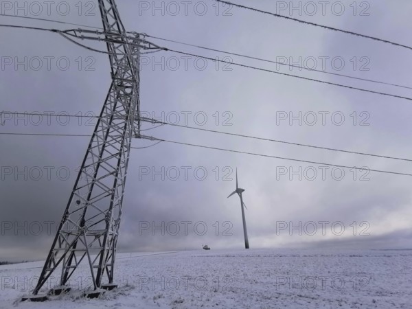 View of a wind turbine and a power pole in a snowy winter landscape, Rennsteig, Frankenwald nature park Park