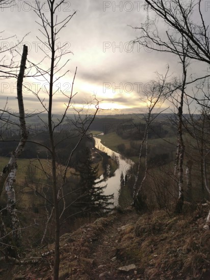 A river snakes through a hilly landscape at sunset, looking across the Saxon Saale from the Petersgratblick viewpoint, Thuringia