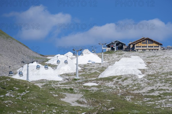 Global warming, artificial snow in piles next to cable car, Brenta, Parco Naturale Brenta-Adamello, Trentino, Italy