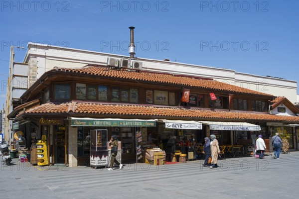Traditional market building with red tile roof surrounded by shops and people, sunny day, Konya, Central Anatolia, Turkey