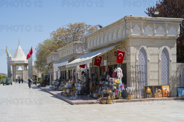 Street scene with shops and waving flags, architectural style, souvenir shops, in the background the war memorial to the victims of the War of Independence, Konya, Central Anatolia, Turkey