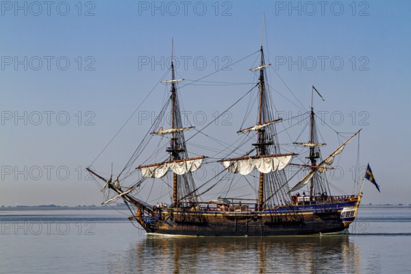 A historic sailing ship with set sails gliding calmly through the water, An old historic sailing ship